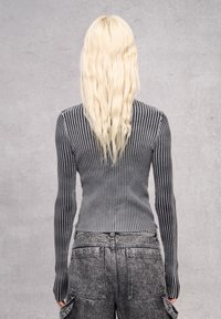 Graues und schwarzes, geripptes Langarmoberteil mit einer figurbetonten Passform, kombiniert mit hochgeschnittenen grauen Cargo-Hosen mit aufgesetzten Taschen und leichter Textur.