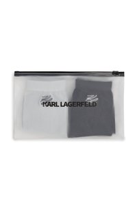 Deux chaussettes pliées, l'une blanche et l'autre noire, à l'intérieur d'une pochette translucide avec une fermeture éclair noire et "KARL LAGERFELD" imprimé dessus.