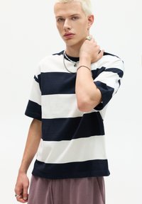 Striped t-shirt in navy and white cotton, short sleeves, relaxed fit. Features bold horizontal stripes and a crew neckline.