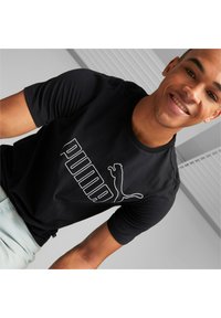 Camiseta de algodón negra con un gran logo blanco de "PUMA" y una silueta de gato, de mangas cortas y con cuello redondo. Ajuste casual.