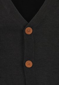 Mörkgrå cardigan med V-halsdesign, som har två runda träknappar framtill i mitten och ett strukturerat stickat material.