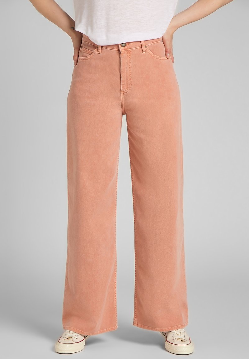 Jeans de pierna ancha, de color durazno, fabricados con un tejido suave, que cuentan con una cintura alta, un diseño clásico de cinco bolsillos y acentos de costura mínimos.