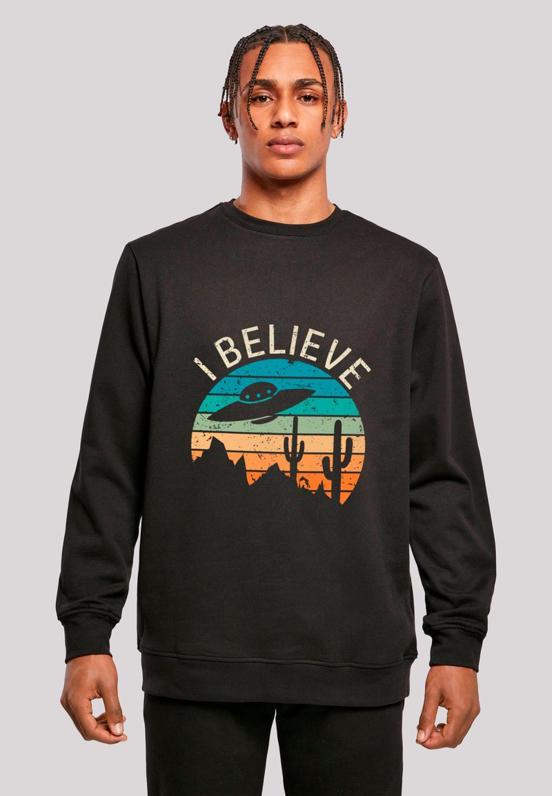 Schwarzer Pullover mit einem Grafikdesign, das ein UFO, Berge und Kakteen auf horizontalen Verlaufstreifen in Blau, Orange und Gelb zeigt.