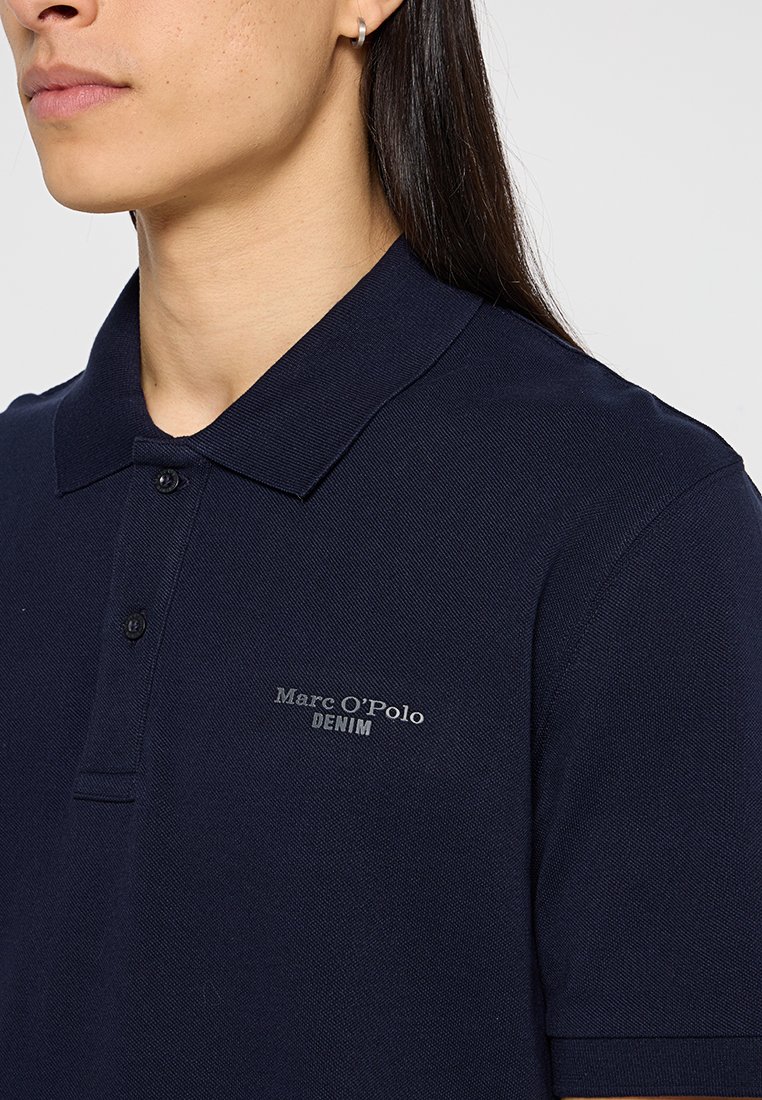 Navyblaues Poloshirt aus strukturierter Stoffqualität mit Kragen, ausgestattet mit einer Zwei-Knopf-Leiste und einem kleinen "Marc O'Polo DENIM"-Logo auf der Brust.