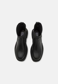 Botas Chelsea de cuero negro con paneles elásticos laterales, punta redondeada y forro texturizado. Cuenta con una lengüeta para facilitar el calzado. Acabado suave.