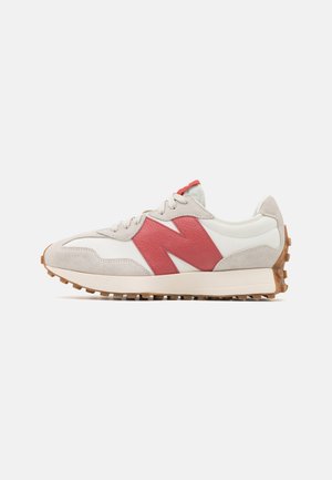 White and beige sneaker with a thick sole, textured red "N" logo on the side, and brown rubber outsole with grip studs.