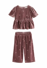 Samt-Zweiteiler in staubigem Rosa. Das Oberteil hat einen Peplum-Stil mit kurzen Puffärmeln und einer Schleife vorne; die Hose ist cropped und hat ein Schleifenmuster.