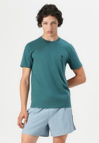 Türkise Baumwoll-T-Shirt mit klassischem Rundhalsausschnitt und kurzen Ärmeln; verfügt über ein kleines gesticktes Logo auf der linken Brustseite.