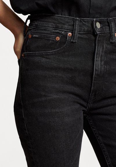 Melni denim džinsi ir ar pieguļošu dizainu, varš pogu un kniedes akcentiem, kā arī vieglu izbalējuma tekstūru. Zīmola etiķete redzama uz kabatas.