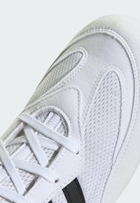 White athletic shoe with mesh and suede materials, featuring a textured surface, lace closure, and a black accent stripe along the side.