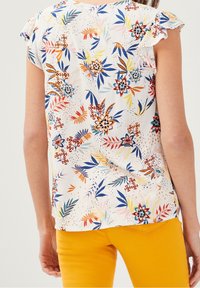 Kortærmet bluse i let stof med et flerfarvet blomsterprint på hvid baggrund og flæser ved ærmeenderne.