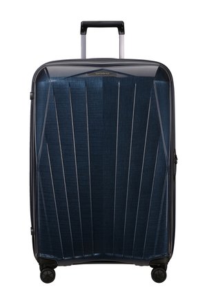 Hard-shell suitcase in dark blue with vertical lines and glossy texture. Features a telescopic handle and four wheels for mobility.
