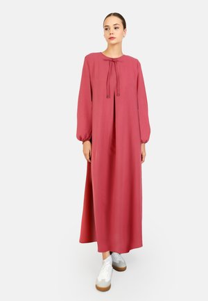 Long, loose-fitting dress in rose color, made of soft fabric, featuring a round neckline with a tie closure and balloon sleeves.