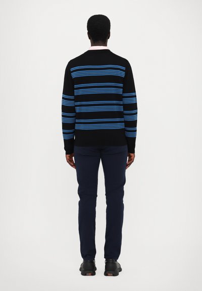Pull noir à rayures horizontales bleues, associé à un pantalon marine. Les manches sont longues et la coupe est standard. Détail de col subtil visible.