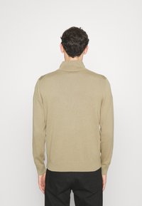 Béžový svetr s vysokým límcem a dlouhými rukávy. Hladká pletená textura s žebrovanými manžetami a lemem. Pohled zezadu, bez viditelných vzorů nebo dekorací.