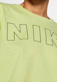Light green short-sleeve t-shirt made of soft cotton, featuring large black outlined letters spelling "NIKE" across the front.