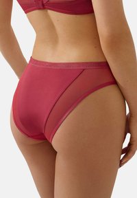 Bordeaux lingerie slip met een gladde voorkant en doorschijnende mesh zijkanten. De tailleband is versierd met een subtiele textuurpatroon.