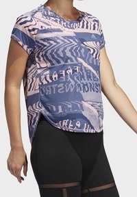 Sportovní tričko s krátkým rukávem v růžové a tmavě modré barvě, s geometrickým vzorem a bočními rozparky pro pohodlí. Doplněno černými legínami.