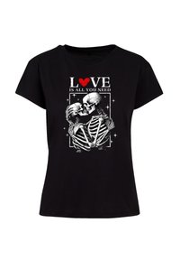 Black t-shirt featuring a graphic of two skeletons holding each other, with text "LOVE IS ALL YOU NEED" and a red heart above.