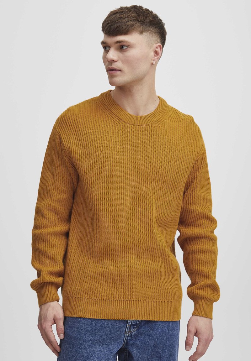 Mustard yellow ribbed knit sweater with a crew neck, long sleeves, and a relaxed fit. Notable texture and even stitching detail.