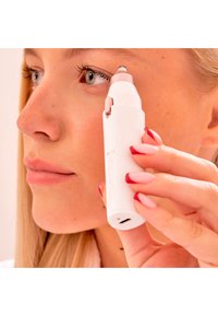 Wit handheld apparaat met een zilveren accent, ontworpen voor gezichtsgebruik. Het heeft een puntige punt en een oplaadpoort aan de basis.