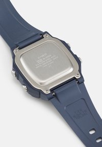 Casio watch with a blue resin strap and stainless steel back. Square case shape, embossed details on the strap, and water-resistant to 10 bar.
