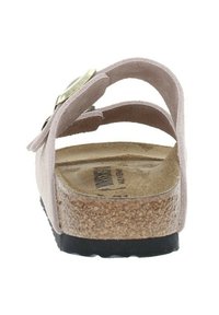 Sandale à semelle glissante en suede rose vue de l'arrière, avec deux brides et une semelle en liège dotée d'une semelle extérieure texturée noire. Détails en accent doré.