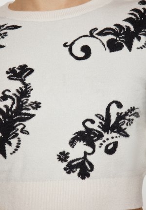 Strikket sweater i creme med sorte blomster mønstre. Har en ribbet rund halsudskæring og en glat tekstur. Mellemlange ærmer.