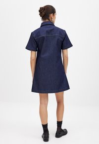 Sinine teksast kleit lühikeste varrukatega, tumeindiigo värv, krae ja kaarjas äär. Omab nähtavat õmblust ja vaba lõiget.