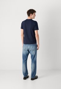 Tricou navy cu mânecă scurtă, material moale, asortat cu blugi deschiși la culoare, design cu picioare drepte, stil clasic cu cinci buzunare, pantofi negri.