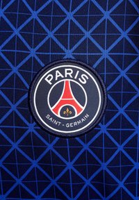 Tissu bleu marine avec un motif géométrique. Élément circulaire en relief avec le texte "PARIS" et "SAINT-GERMAIN" et un design de la Tour Eiffel rouge.