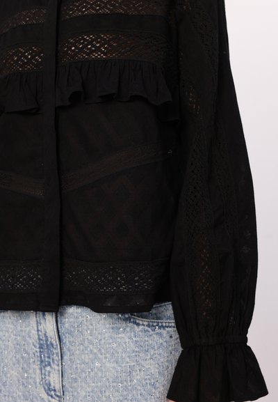 Schwarze Bluse mit aufwendigen Spitzeneinsätzen, Rüschenakzenten und langen Ärmeln mit gerafften Manschetten. Strukturierter Stoff mit einem mehrschichtigen Design.