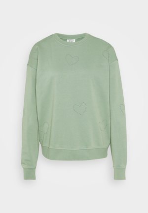 Lys grønn hettegenser laget av mykt materiale med avslappet passform. Har hjerteformede dekorasjoner og ribbestrikkede mansjetter og hem.