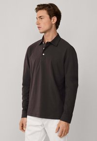 Polo a maniche lunghe di un intenso colore antracite, con colletto classico, tre bottoni e una texture di cotone liscia. Presenta un orlo dritto e cuciture laterali.