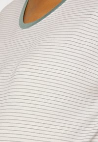 Camiseta listrada com decote redondo; cor de base branca com finas listras cinzas e um colarinho verde em contraste. Tecido suave e leve.