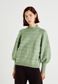 Green knitted sweater featuring a high neck, textured pattern, and balloon sleeves, complemented by ribbed hems for added detail.
