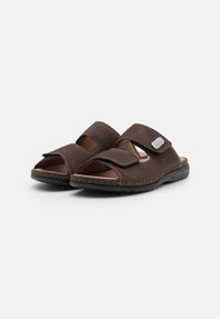 Dunkelbraune offene Sandalen aus weichem Leder, mit zwei verstellbaren Klettverschluss-Riemen und einer gepolsterten Innensohle auf einer flexiblen schwarzen Sohle.