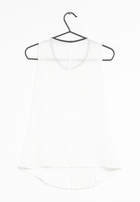 Top sans manches blanc avec un col rond, présentant un ourlet légèrement incurvé et des plis subtils à l'arrière pour plus de texture. Suspendu à un crochet noir.