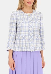 Jasnoniebieska marynarka tweedowa z białymi akcentami o teksturowanym wykończeniu, z okrągłym dekoltem, przednimi kieszeniami oraz postrzępionymi brzegami rękawów.