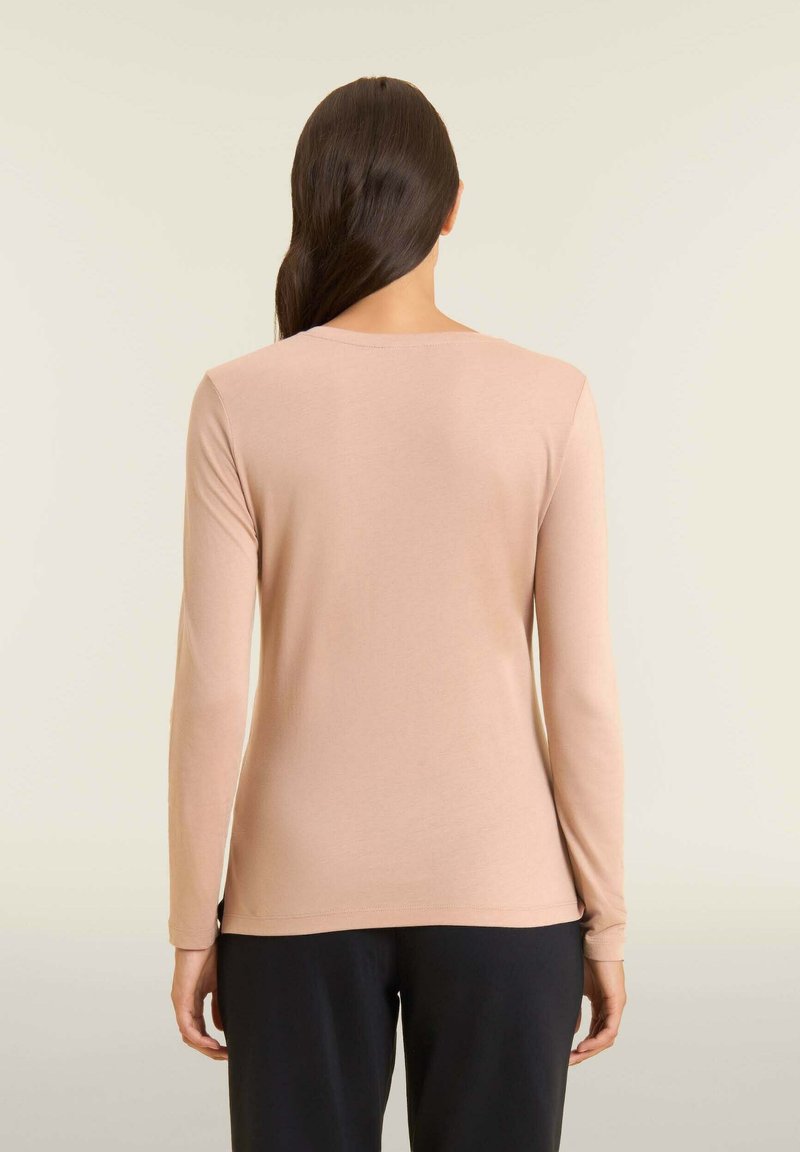 Maglione a maniche lunghe in beige chiaro, realizzato in tessuto morbido. Caratterizzato da un collo rotondo e un design aderente, abbinato a pantaloni neri.