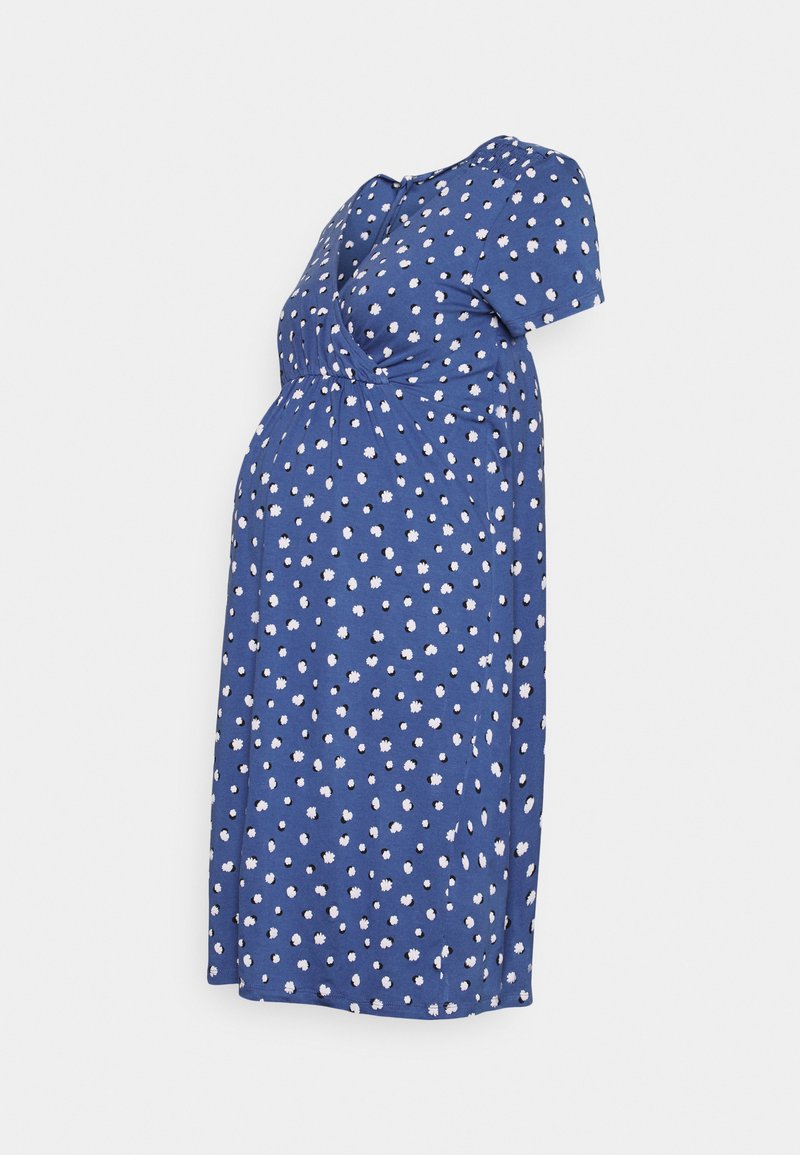 Vestido de maternidade azul com bolinhas brancas, mangas curtas e detalhe de nó sob o busto, feito de um tecido leve.