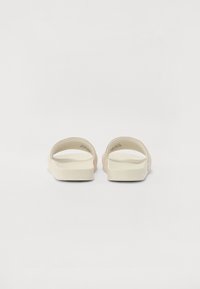 Des sandales à enfiler de couleur beige clair avec une finition lisse et mate. Elles présentent des sangles larges, des bords arrondis et une semelle épaisse et rembourrée pour plus de confort.
