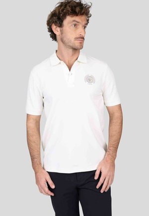 Chemise polo blanche à manches courtes, avec un col et un logo brodé sur la poitrine gauche. Fabriquée en matériau lisse et léger.