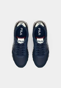 Dark blue athletic shoes with white accents and laces, featuring a textured sole and the Fila logo on the tongue and sides.