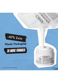 Crème Ultra Facial de Kiehl's dans un contenant blanc avec un couvercle texturé, accompagnée d'un sachet de recharge transparent. Fond bleu avec un texte en gras.