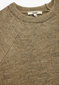 Beige gestrickter Pullover mit Rundhals und langen Raglanärmeln. Das Material hat eine strukturierte Oberfläche mit einem dezenten Melange-Muster. Markenlabel sichtbar.