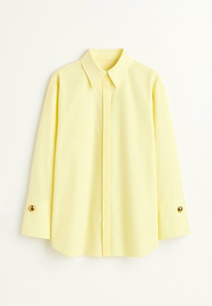 Lysegul langærmet skjorte med spidst krave, skjulte knapper foran og guld manchetknapper på ærmerne.