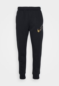 Černé tepláky vyrobené z měkké tkaniny, s zlatým logem Nike swoosh a bílým nápisem "Just Do It" na přední straně. Design se zužujícími se nohavicemi.