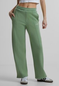 Groene sweatpants met een ontspannen pasvorm, elastische tailleband, zijzakken en subtiele stikdetails. Merklogo gedrukt op de dij.
