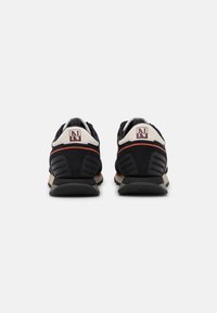 Scarpe atletiche nere e grigie con una morbida tomaia in suede e mesh, dotate di un copri tallone bianco, accenti rossi e suola in gomma testurizzata.